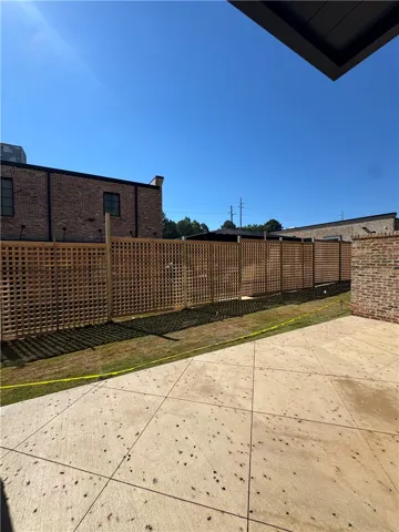 A spacious concrete patio bordered by tall wooden lattice fencing under clear blue skies.