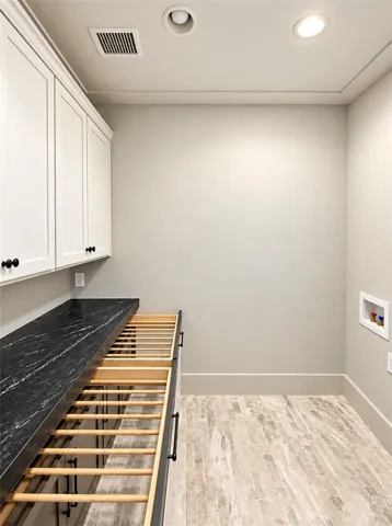 A functional laundry space featuring stone countertops, built-in cabinetry, and tile flooring.