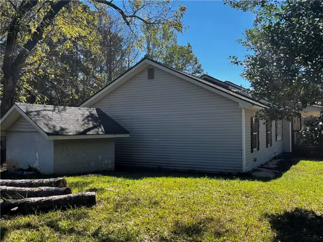 Mature trees frame the side profile of this classic single-story home with a neat lawn.