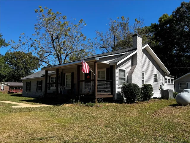 Classic siding exterior features a welcoming covered front porch and a brick fireplace chimney.