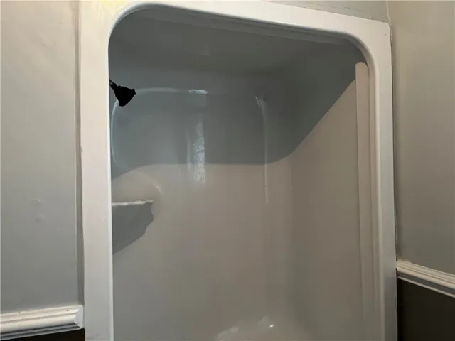A clean shower stall insert with a molded shelf matches the classic trim detailing.