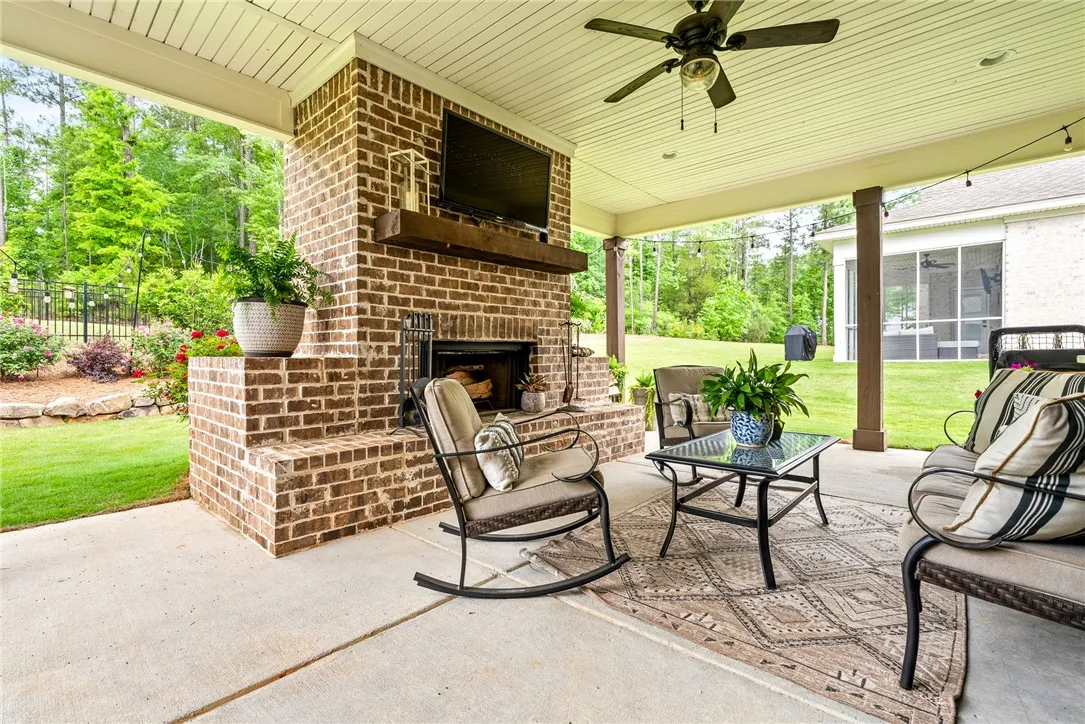 Covered patio with a brick fireplace and ceiling fans.