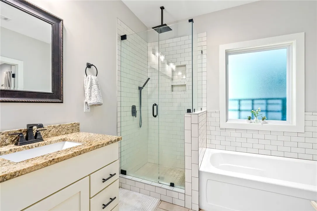 Tiled walk-in shower with glass door, plus a separate tub.