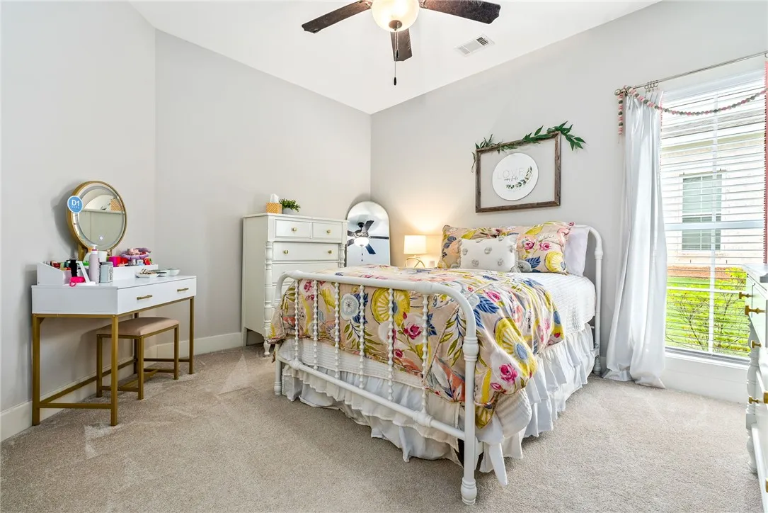 Bedroom with a ceiling fan and two windows.