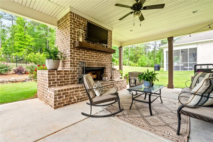 Covered patio with a brick fireplace and ceiling fans.
