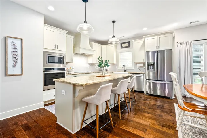 Kitchen with a large island, bar seating, and stainless appliances.