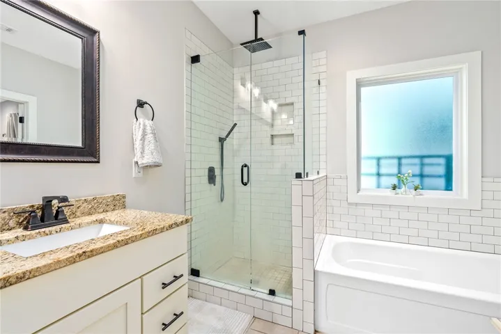 Tiled walk-in shower with glass door, plus a separate tub.