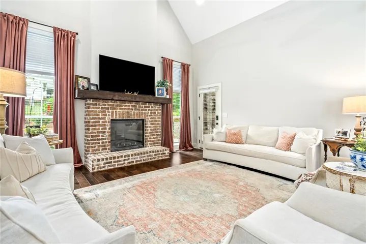 Living room with a brick fireplace, vaulted ceiling, and lots of windows.