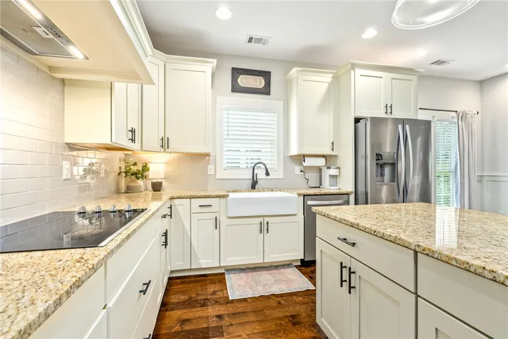 White shaker cabinets, granite counters, and a farmhouse sink.