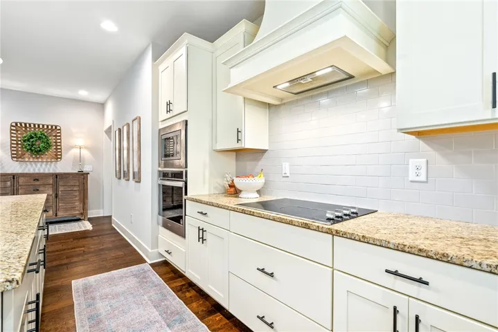 Cooktop with a vent hood and a subway tile backsplash.