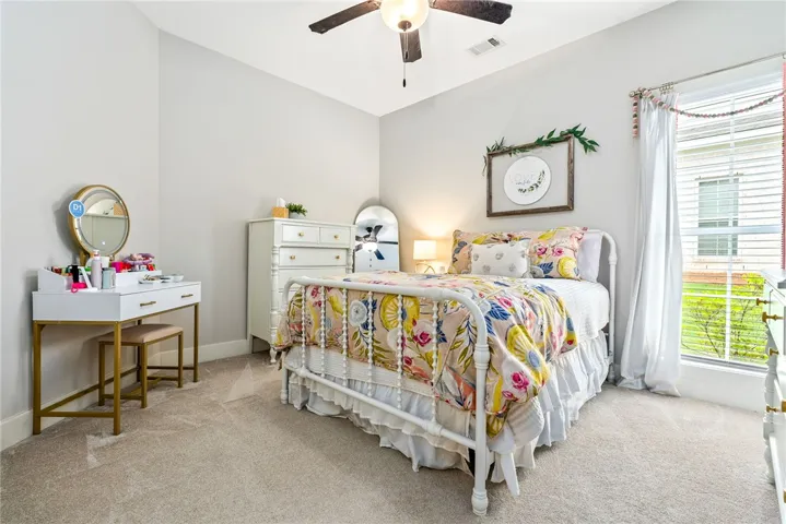 Bedroom with a ceiling fan and two windows.