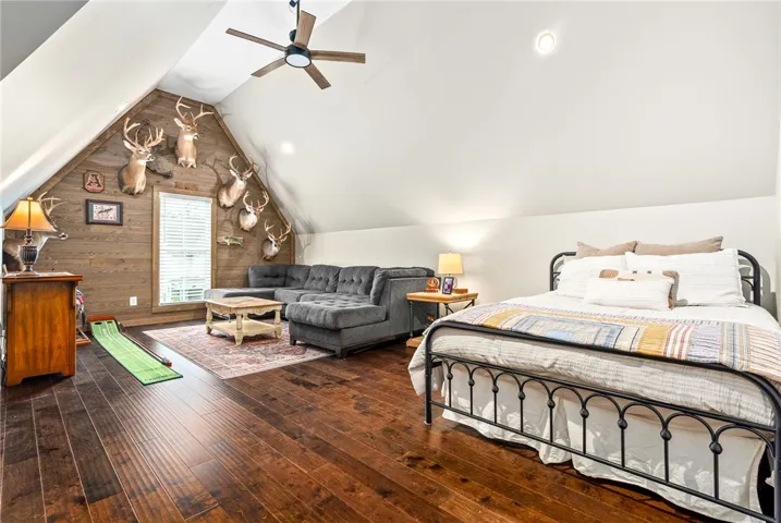 Bonus room with a vaulted ceiling, hardwood floors, and a wood accent wall.
