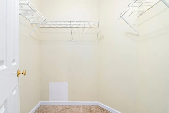 Ample storage potential awaits in this walk-in closet featuring built-in wire shelving and plush carpeting.