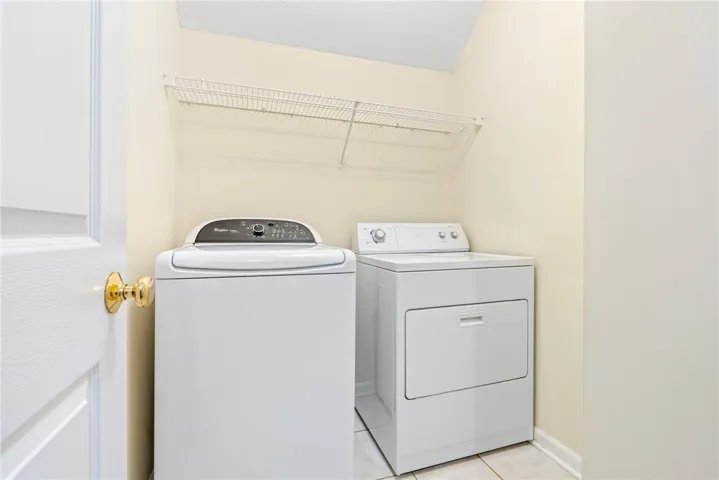 Functional laundry setup highlights tiled flooring and integrated wire shelving overhead.