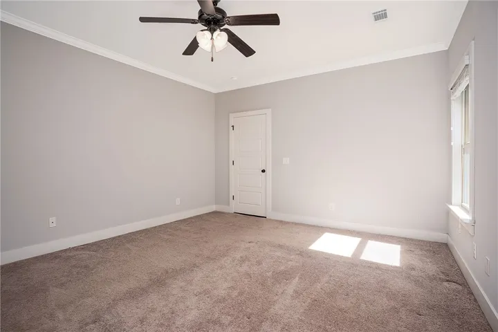 Soft plush carpeting and clean crown molding define this versatile, neutral-toned room.