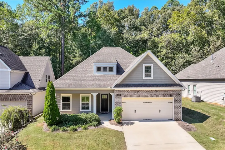 An inviting exterior displays brick and siding accents set against a lush woodland backdrop.