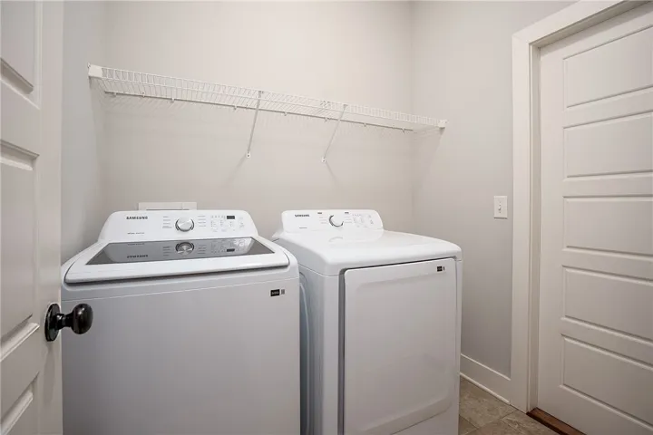 Functional laundry setup featuring built-in wire shelving and tile flooring.