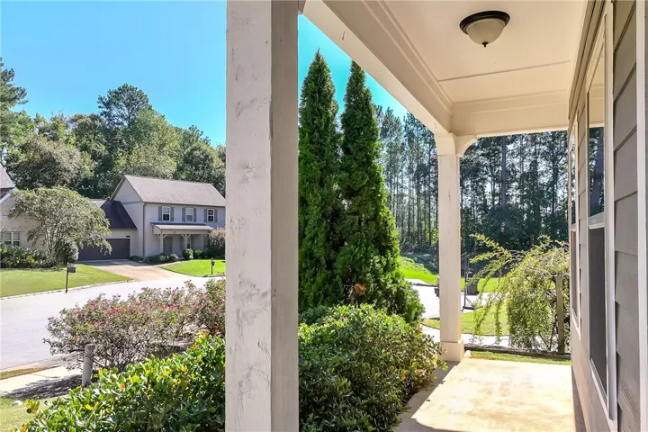 An inviting covered front porch overlooks a manicured lawn and mature neighborhood trees.