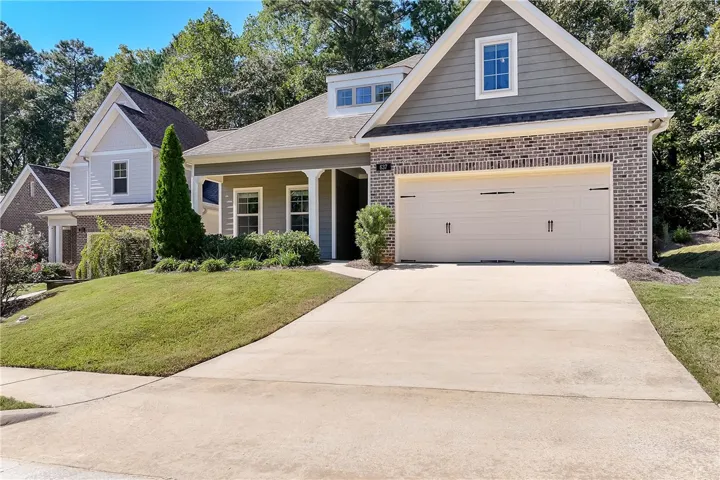 A concrete driveway leads to a classic home featuring mixed brick and siding architecture.