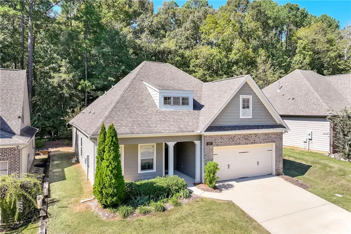 A classic brick and siding exterior stands framed by mature trees and manicured lawns.