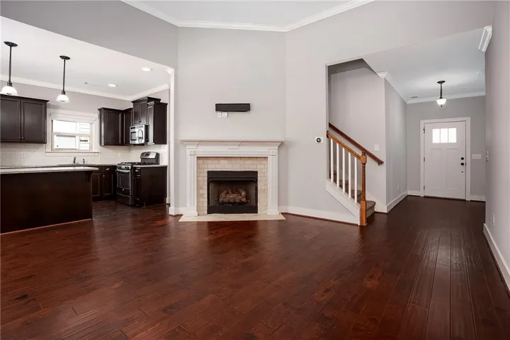 Rich hardwood flooring complements a classic fireplace and seamless transitions between functional living zones.