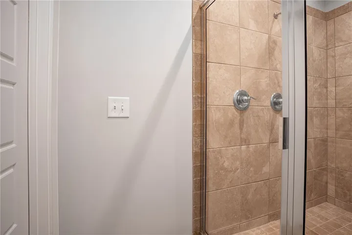 Elegantly tiled walk-in shower features dual shower heads and glass doors.
