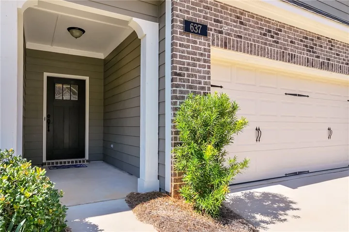 A welcoming covered entryway features brick and siding accents alongside a spacious garage.