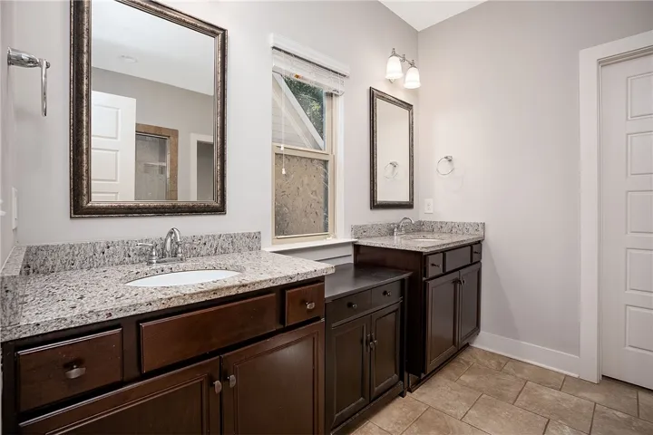 A spacious layout features two separate dark wood vanities paired with durable granite countertops.