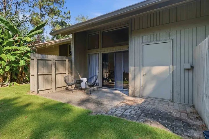 A secluded paved patio area bordered by classic wood fencing features floor-to-ceiling windows.