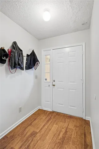 Warm wood flooring and a classic panel door with sidelight welcome guests into the home.