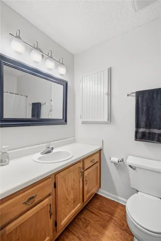 A classic vanity with wooden cabinetry complements the warm wood-look flooring in this bathroom.