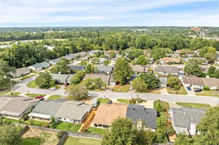 An aerial perspective showcases the neighborhood layout with surrounding mature trees.