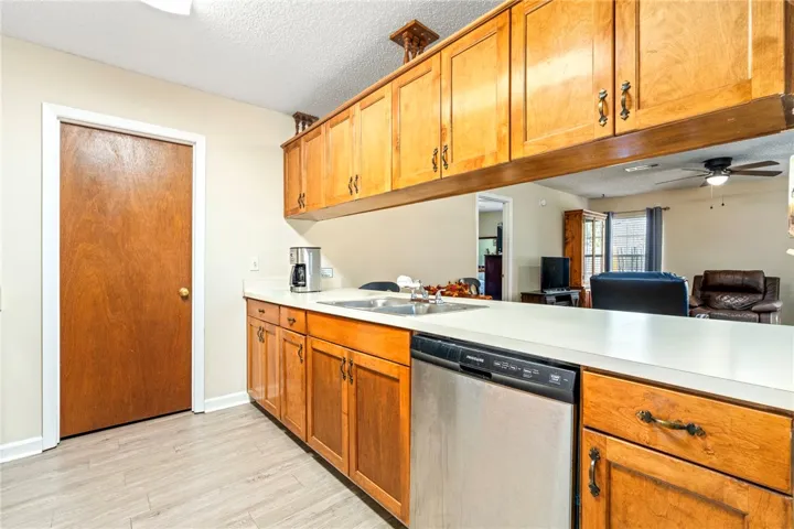 Warm wood cabinetry and durable flooring frame this practical kitchen layout overlooking the living area.