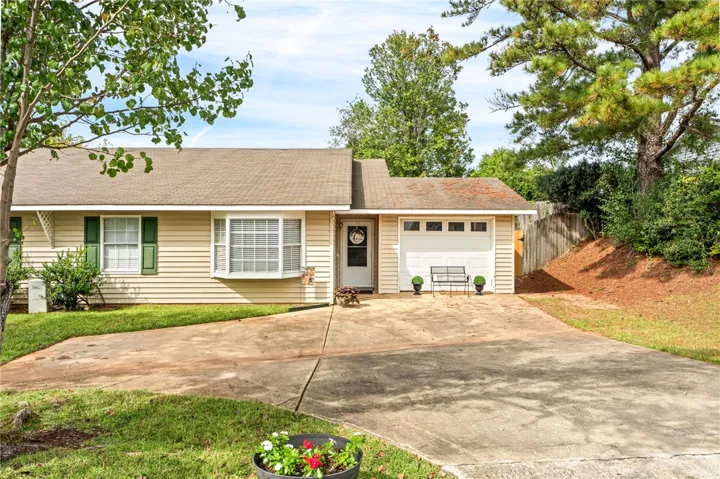 A classic exterior architecture with a paved driveway, attached garage, and charming bay window design.