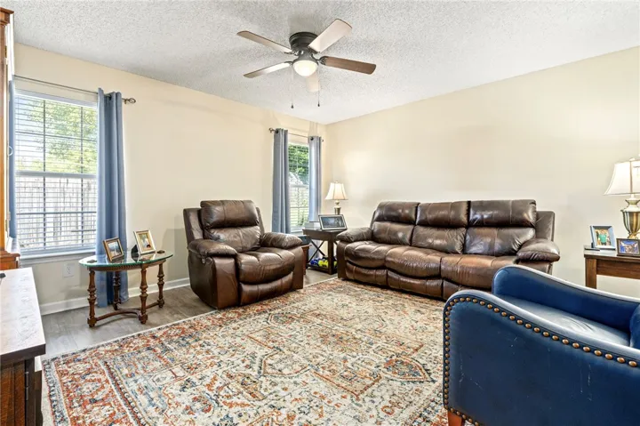A spacious living area features vinyl plank flooring and abundant natural light from multiple windows.