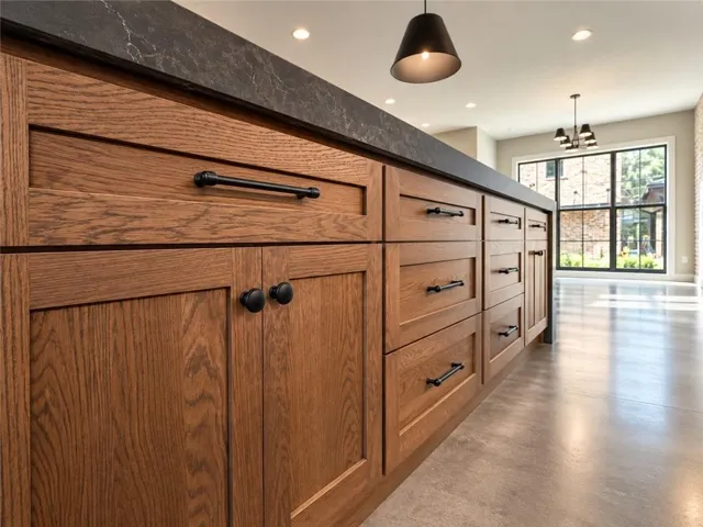 Gleaming polished concrete floors complement custom oak cabinetry beneath a thick stone kitchen island.