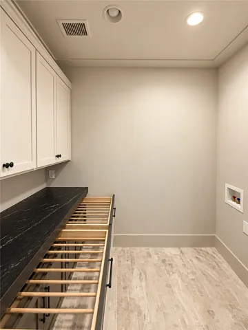A functional laundry area features stone countertops, built-in cabinetry, and textured tile flooring.