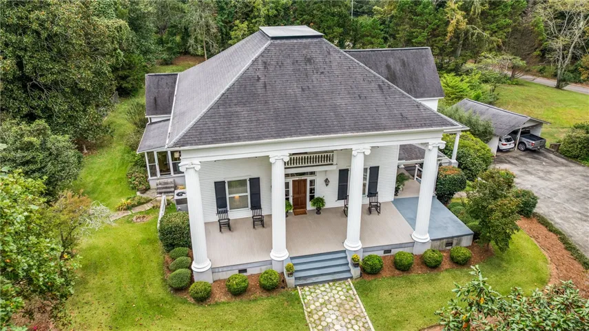 Stately columns and a classic front porch define this historic residence set amidst lush green landscaping.