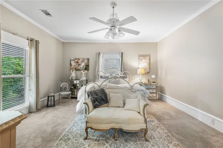 Soft carpeting, classic crown molding, and tall windows design a serene, light-filled retreat.