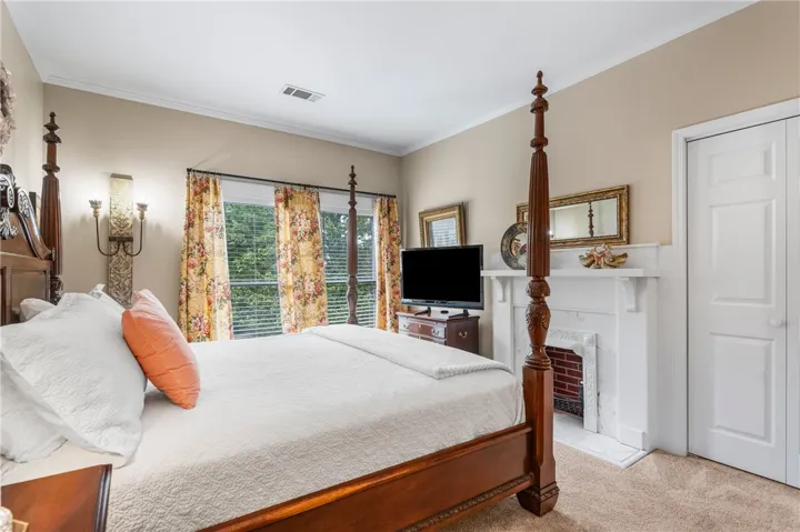 An elegant bedroom features a classic fireplace mantle and crown molding.