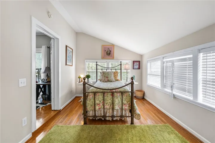 Rich hardwood flooring complements the vaulted ceiling and abundant natural light in this cozy bedroom.