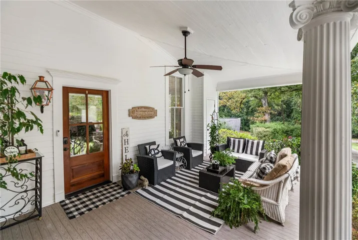 A spacious covered porch features classic columns, clean wood paneling, and warm wood flooring.