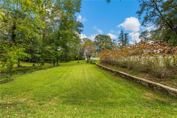 Mature trees frame a wide, grassy lawn bordered by stone retaining walls.
