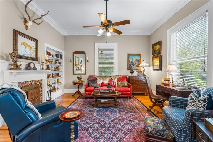 Rich hardwood flooring, crown molding, and a classic fireplace define this inviting living space.