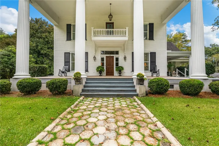 Grand columns flank the entrance of this historic estate with a stone pathway leading inside.