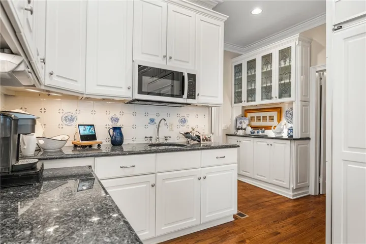 Polished stone countertops complement the timeless cabinetry and warm hardwood flooring in this butler pantry.