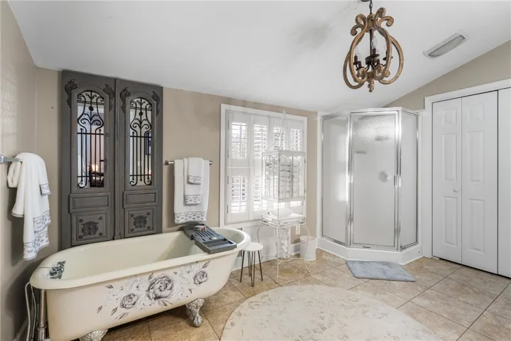 Tiled flooring and a separate corner shower frame the traditional soaking tub area.