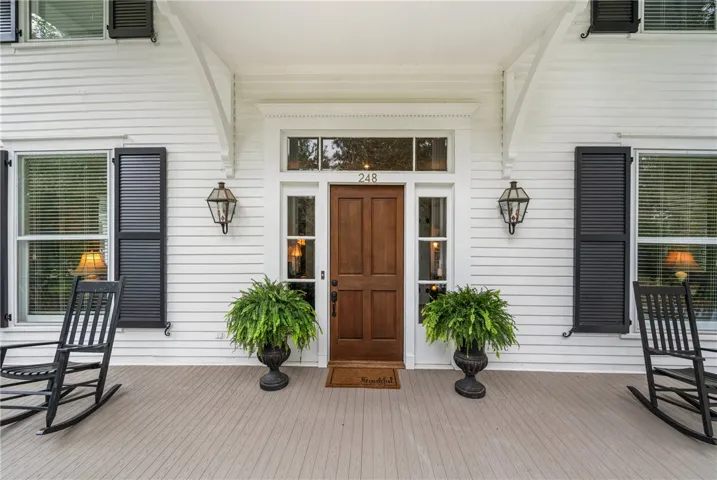 A classic front porch features a rich wood door, flanked by traditional shutters and sidelights.