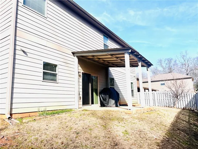 A covered patio overlooks the grassy backyard enclosed by classic white fencing.