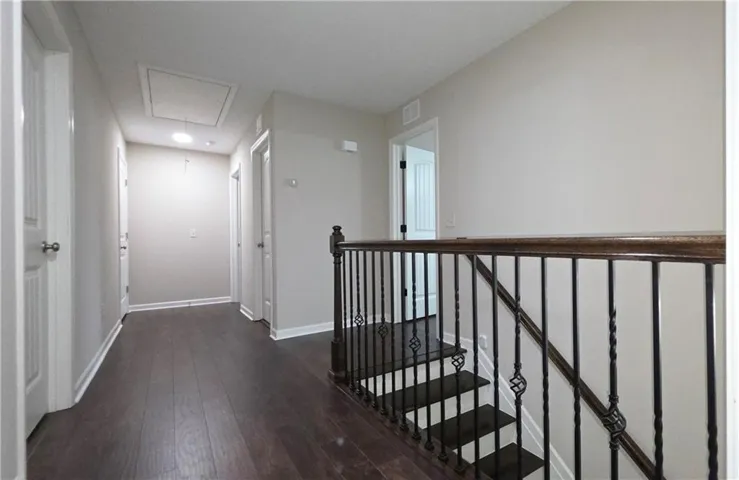 Rich wood flooring runs throughout the upper landing, accented by a classic wrought-iron balustrade.